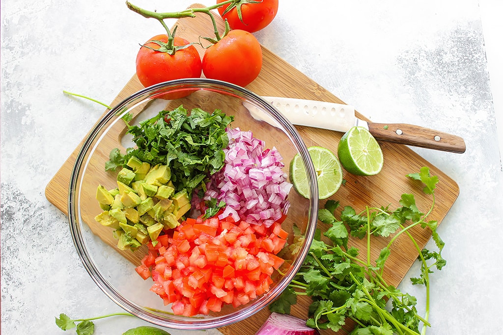 A quick and easy recipe for Pico De Gallo (Salsa Fresca) with fresh avocado, tomatoes, red onions, lemon juice and cilantro. Use it as a dip or topping for tacos!