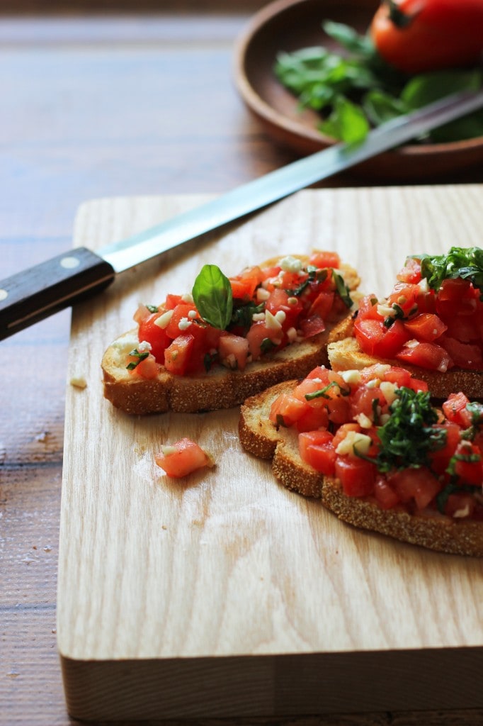 A healthy appetizer of grilled baguette slices rubbed with fresh garlic and topped with tomatoes, garlic, basil and crumbled feta cheese.