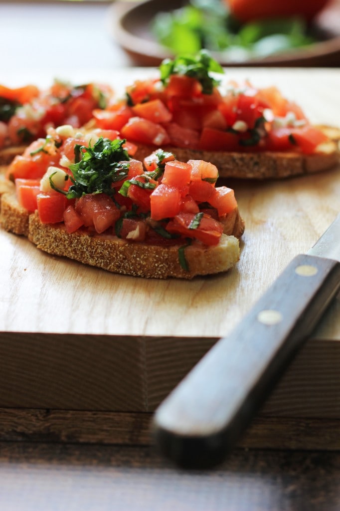 A healthy appetizer of grilled baguette slices rubbed with fresh garlic and topped with tomatoes, garlic, basil and crumbled feta cheese.