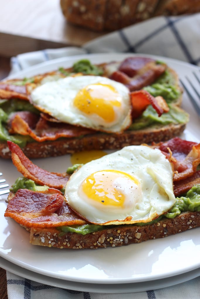 This open-faced breakfast sandwich is a quick and easy fix for mornings or brunch with chilled guacamole spread, crisp bacon and sunny side up eggs.