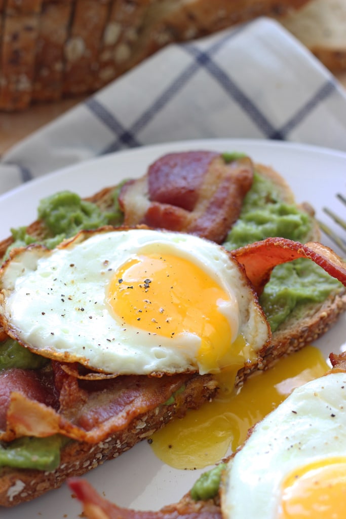 This open-faced breakfast sandwich is a quick and easy fix for mornings or brunch with chilled guacamole spread, crisp bacon and sunny side up eggs.