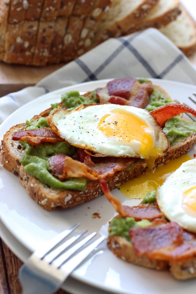 This open-faced breakfast sandwich is a quick and easy fix for mornings or brunch with chilled guacamole spread, crisp bacon and sunny side up eggs.
