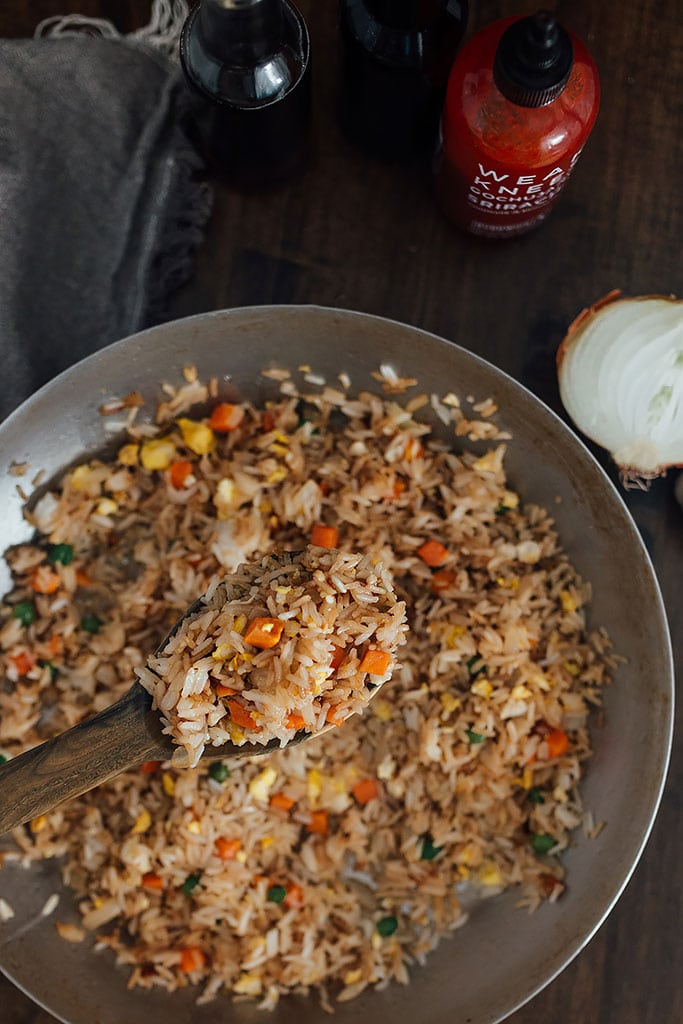 Hibachi-style fried rice in a wok with sauces on the side.