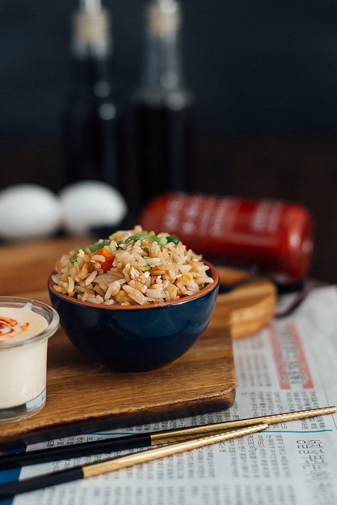 A bowl of hibachi-style fried rice with yum yum sauce and chopsticks.