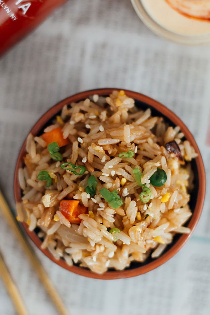 A top down shot of hibachi-style fried rice with yum yum sauce on an old newspaper.