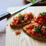 A healthy appetizer of grilled baguette slices rubbed with fresh garlic and topped with tomatoes, garlic, basil and crumbled feta cheese.