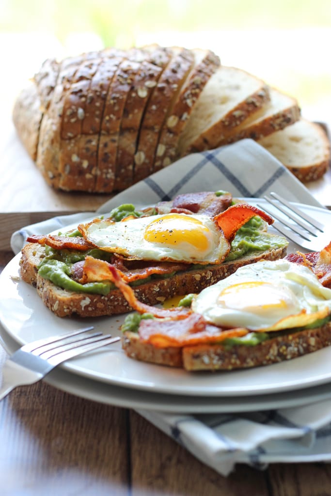 This open-faced breakfast sandwich is a quick and easy fix for mornings or brunch with chilled guacamole spread, crisp bacon and sunny side up eggs.