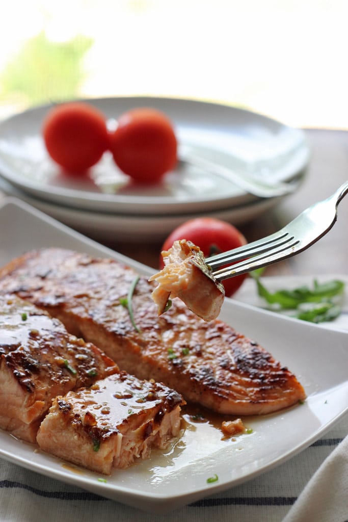 Two honey garlic salmon fillets on a white plate.