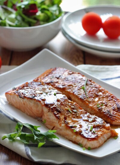 Two fillets of honey garlic salmon on a white plate.