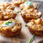 Several mashed potato puffs topped with sour cream and fresh chopped chives.