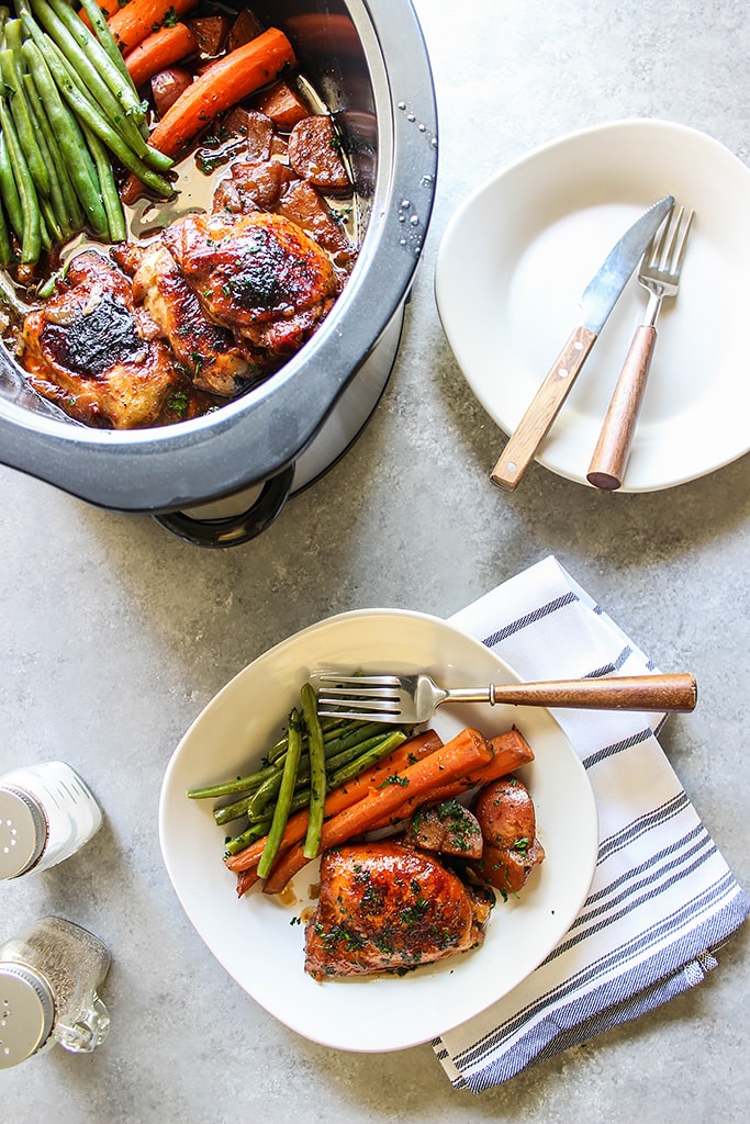 Artistic show of slow cooker honey garlic chicken on a plate and in a slow cooker.