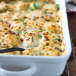 Spinach and artichoke ravioli bake in a white casserole dish.