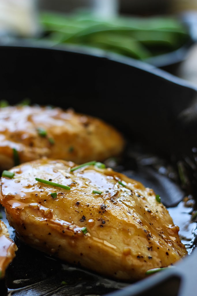 A close up of a maple glazed chicken breast in a cast iron skillet.