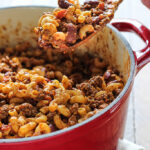 Chili mac and cheese on a wooden spoon.