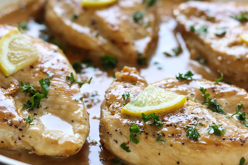 Close up of chicken with lemon garlic cream sauce in a pan.