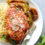 Chicken Cacciatore on bed of spaghetti topped with freshly grated Parmesan cheese and basil.