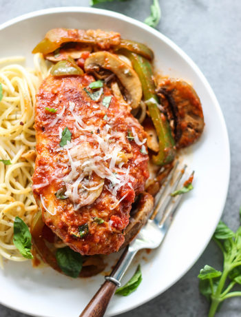 Chicken Cacciatore on bed of spaghetti topped with freshly grated Parmesan cheese and basil.