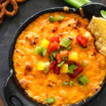 A cast iron bowl of hot buffalo chicken dip.