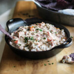 Cream cheese sausage dip in a cast iron bowl with some purple tortilla chips.