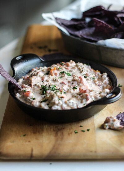 Cream cheese sausage dip in a cast iron bowl with some purple tortilla chips.