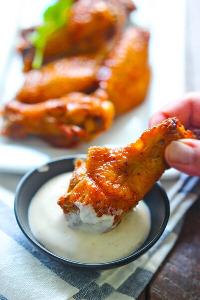 Buffalo wings dipped into a bowl of ranch dressing.