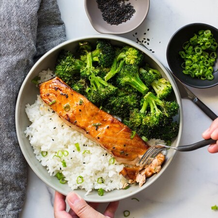 A top down picture of air fryer honey garlic salmon in a bowl with rice and broccoli.