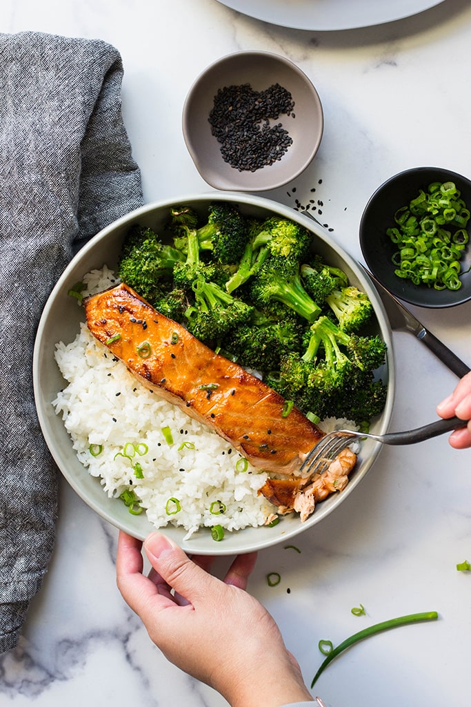 A top down picture of air fryer honey garlic salmon in a bowl with rice and broccoli.