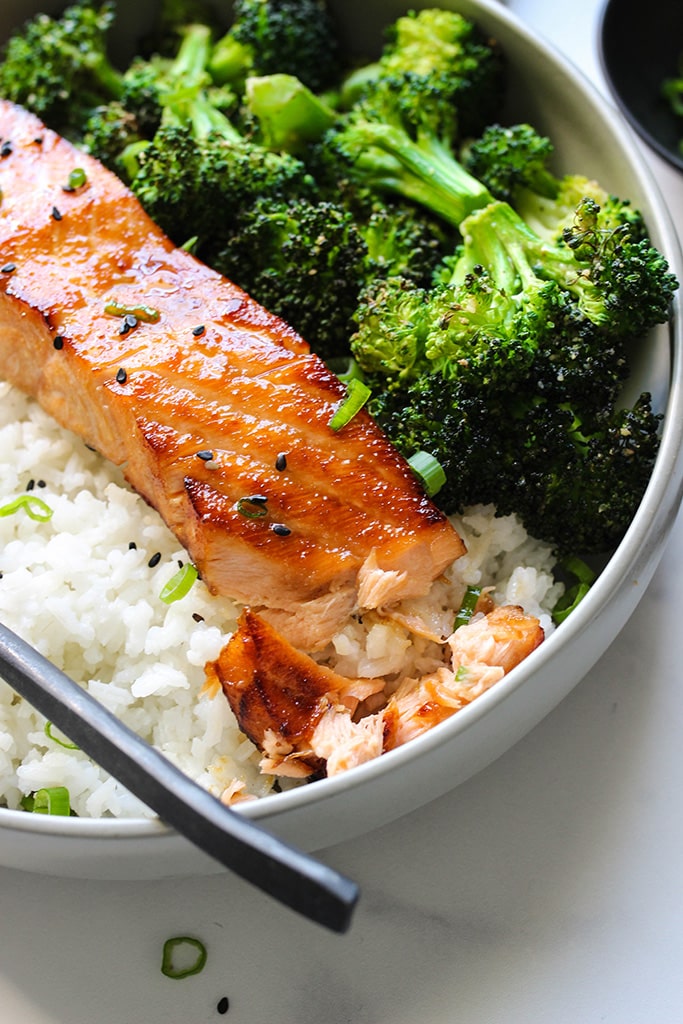 A close up shot of air fryer honey garlic salmon flaked apart with a fork.