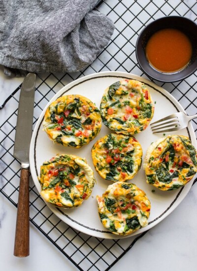 Healthy egg white muffin breakfast cups on a white plate with hot sauce.