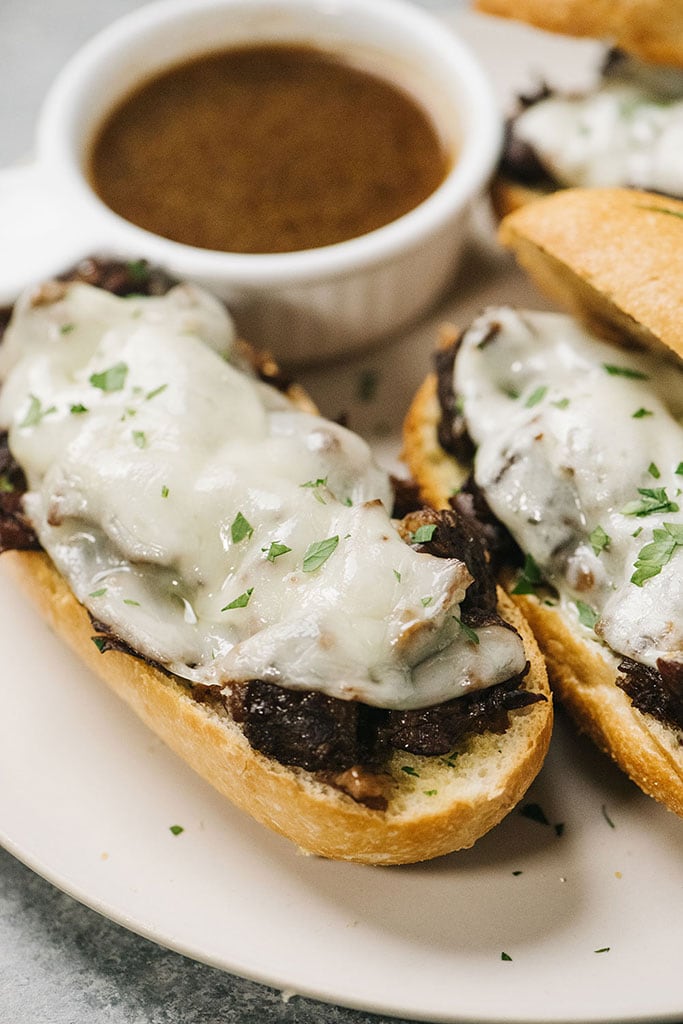 An angled shot of melted provolone cheese and shredded roast beef on hoagies.