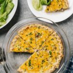 A hamburger quiche on a pie plate with some salad.