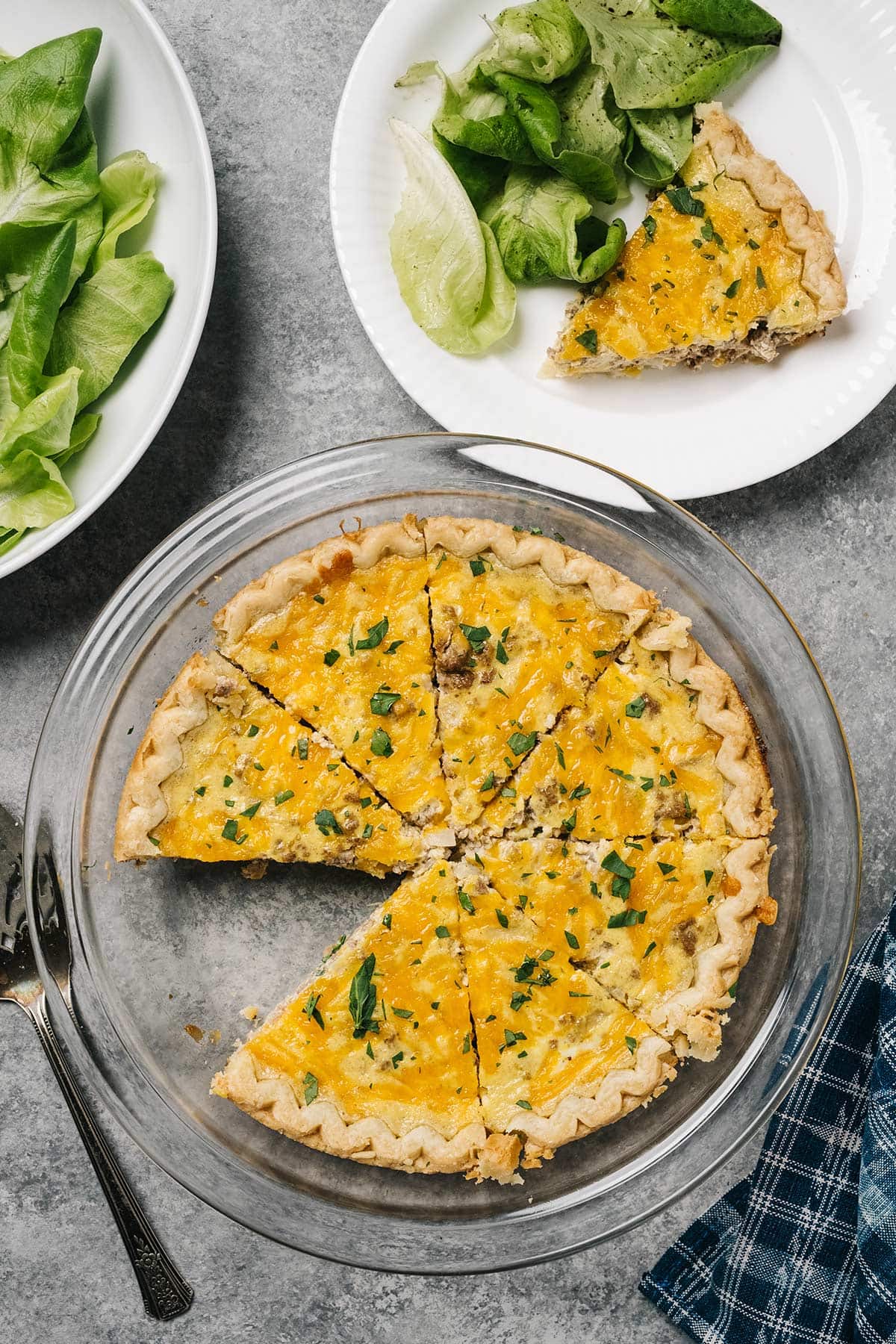 A hamburger quiche on a pie plate with some salad.