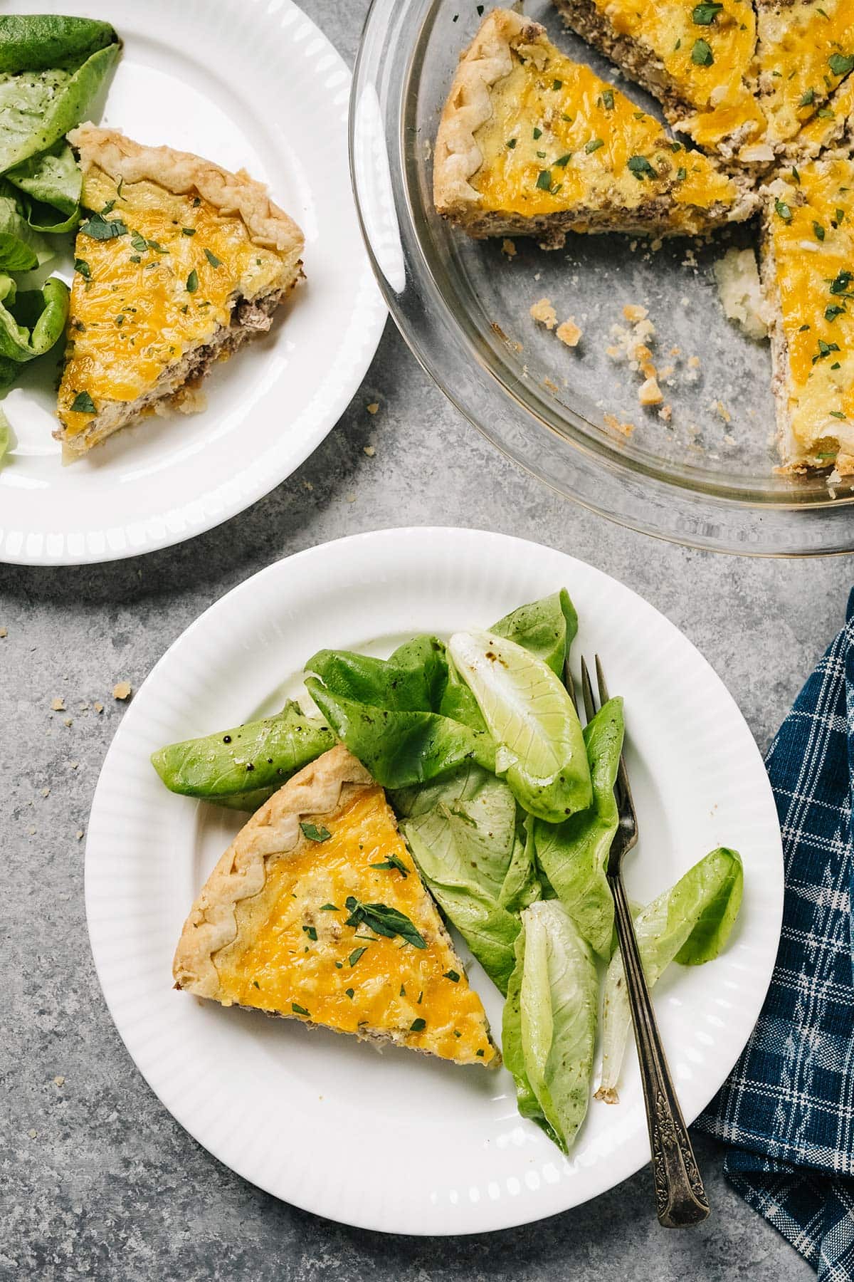 A hamburger quiche on a pie plate with some salad.