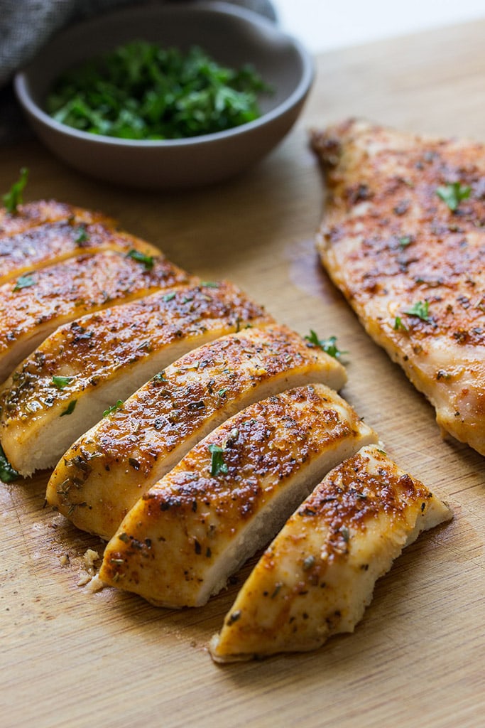 Sliced oven-baked chicken breasts on a cutting board.