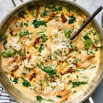 A top down photo of creamy garlic Tuscan shrimp in a skillet topped with fresh parsley.