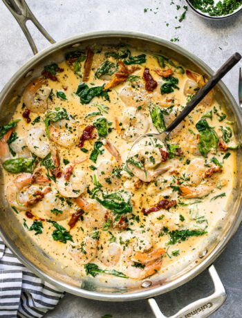 A top down photo of creamy garlic Tuscan shrimp in a skillet topped with fresh parsley.