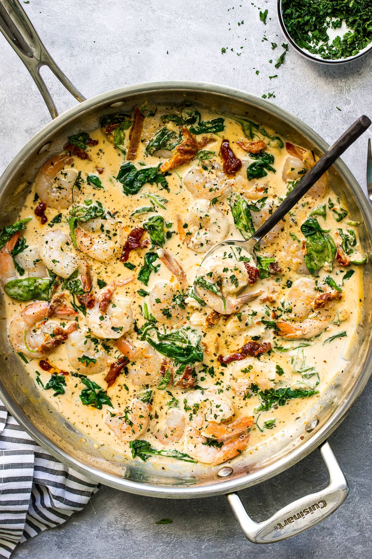 A top down photo of creamy garlic Tuscan shrimp in a skillet topped with fresh parsley.