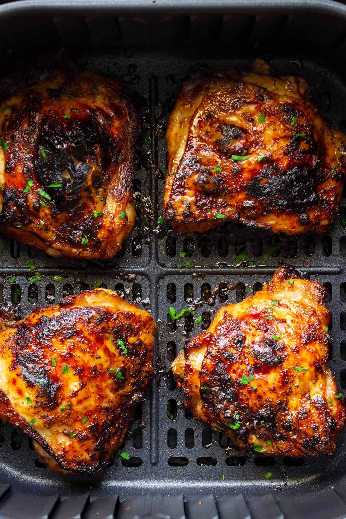 Air fryer maple chicken thighs in an air fryer insert.