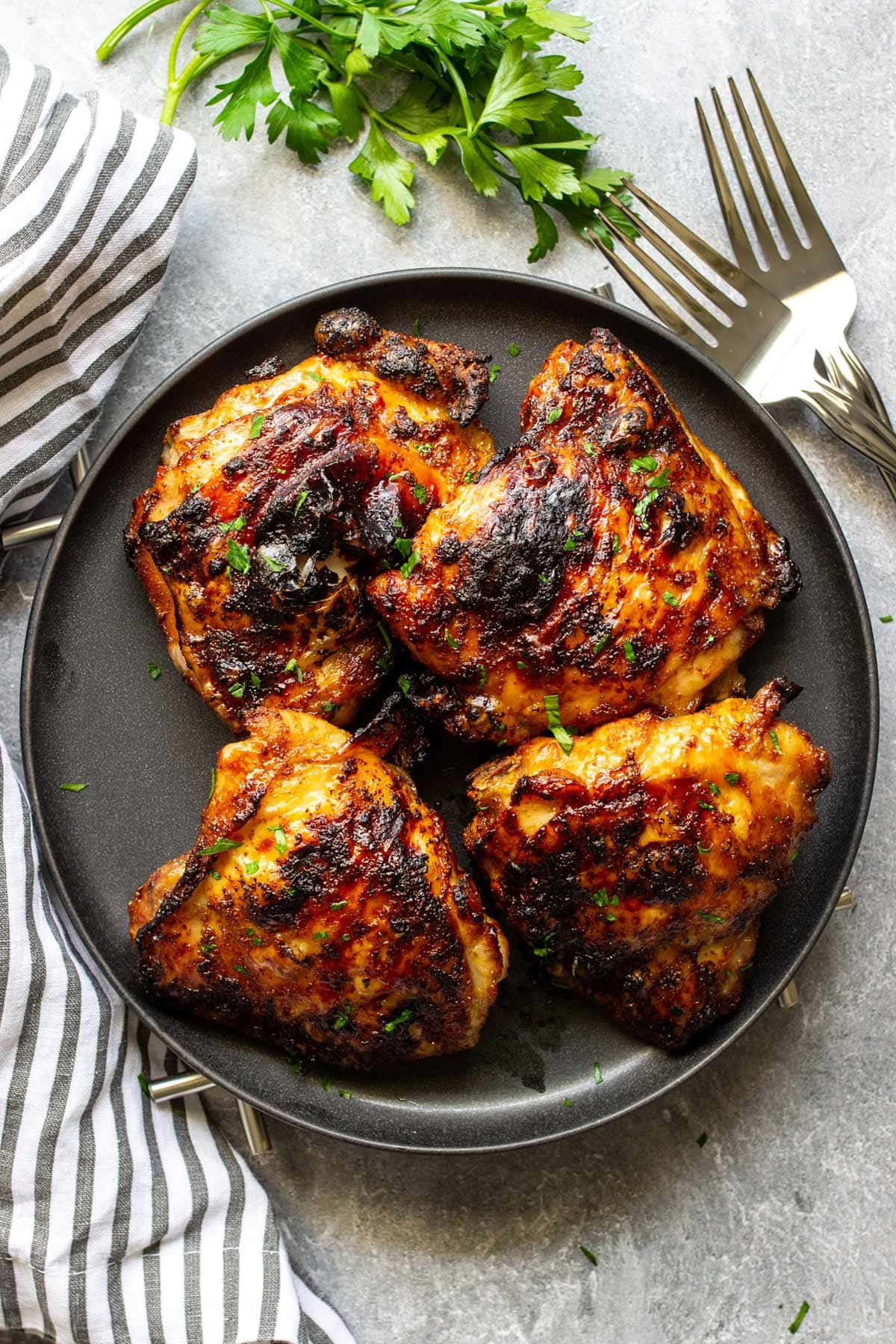 A black plate full of crispy air fryer maple chicken thighs.