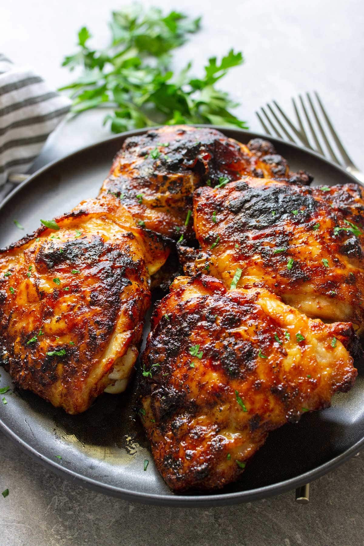 A black plate full of crispy air fryer maple chicken thighs.