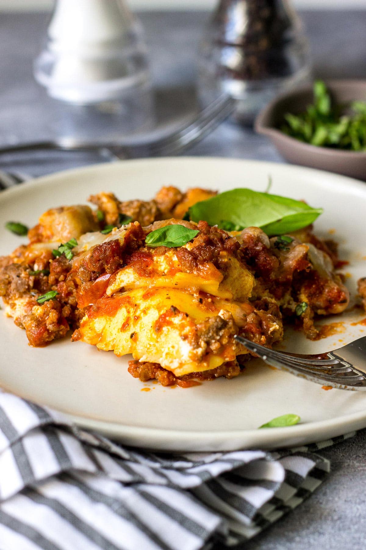 A hearty serving of ravioli lasagna on a plate topped with fresh basil.