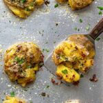 Crispy garlic Parmesan smashed potatoes on a baking sheet topped with fresh parsley.