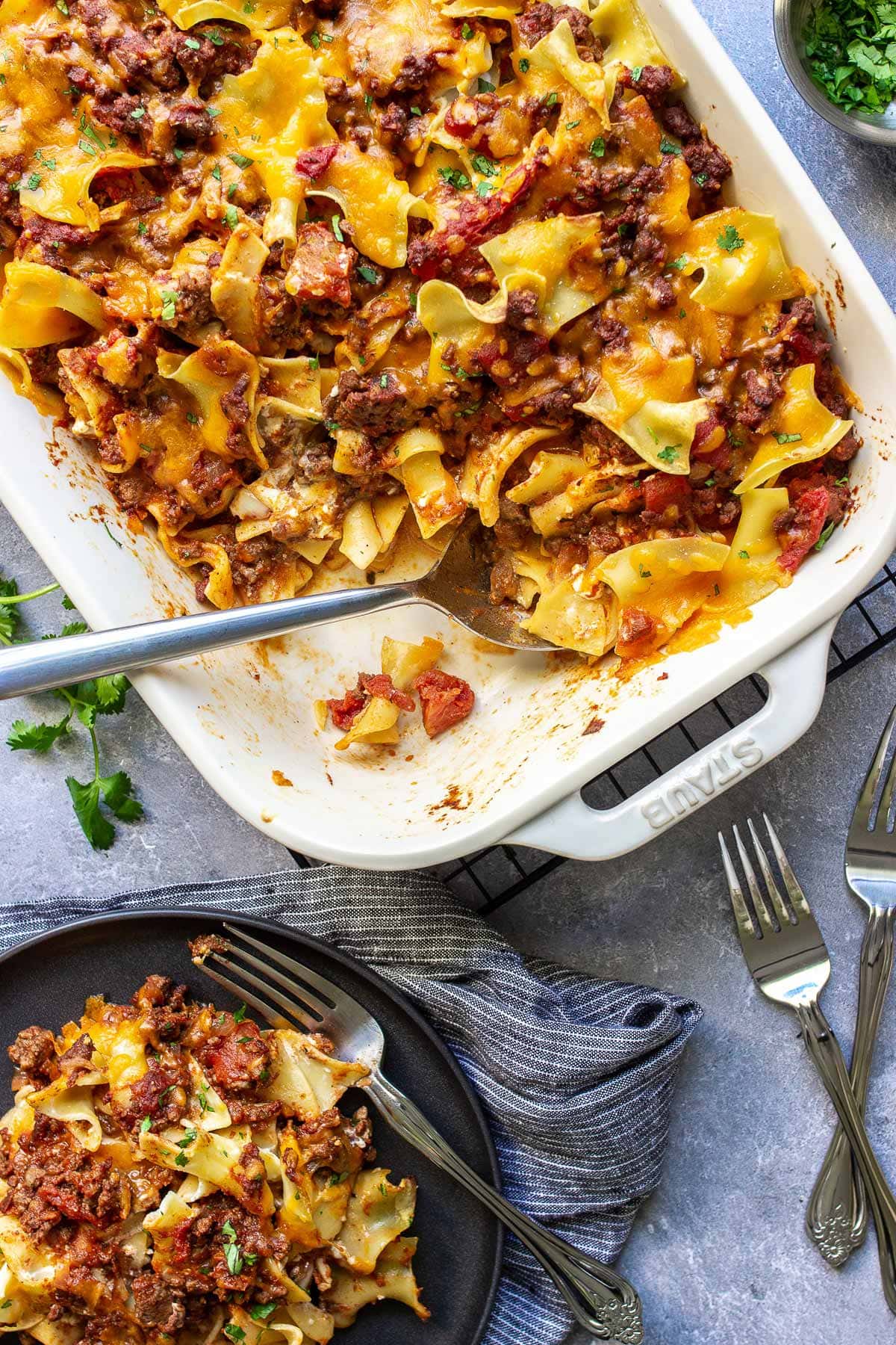 A plate of sour cream beef noodle casserole next to a casserole dish.