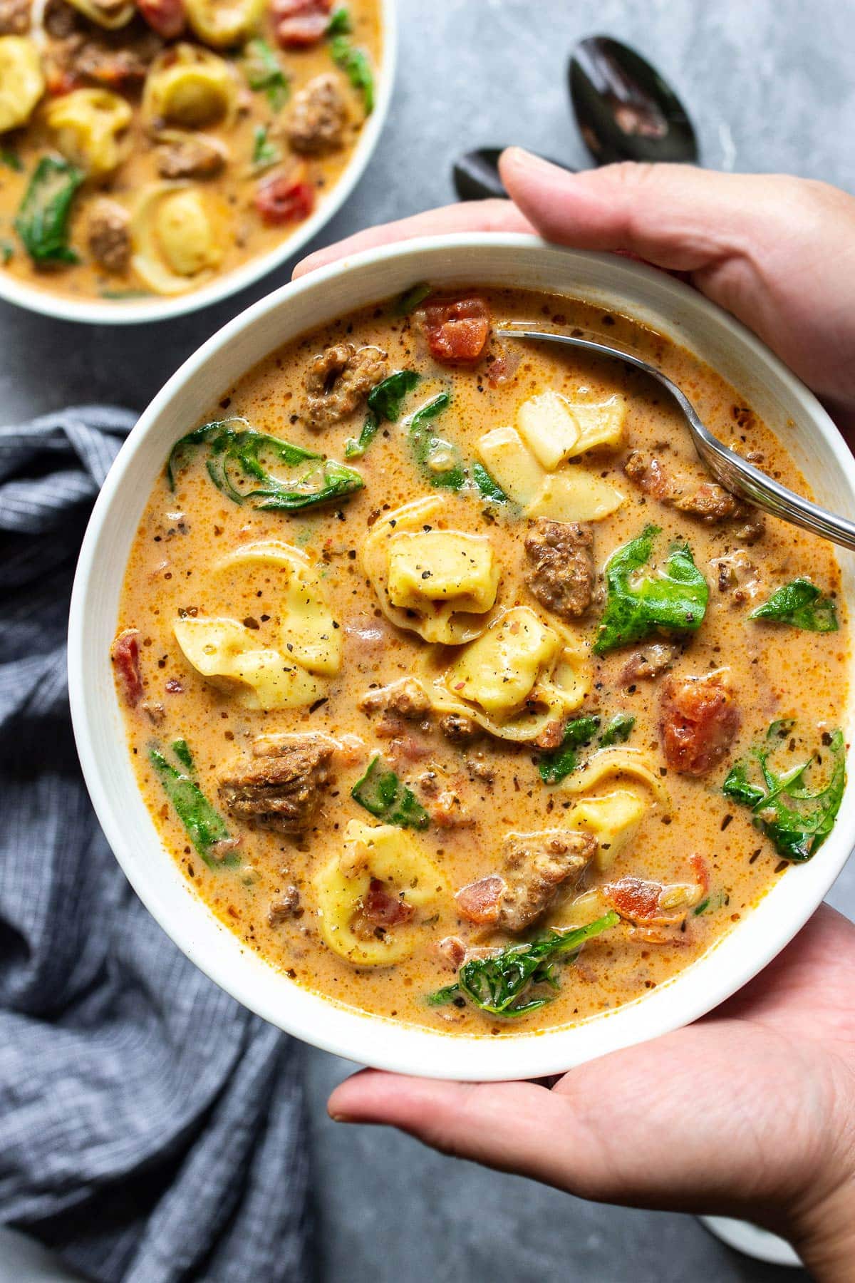 Slow cooker creamy tortellini soup in a white bowl.