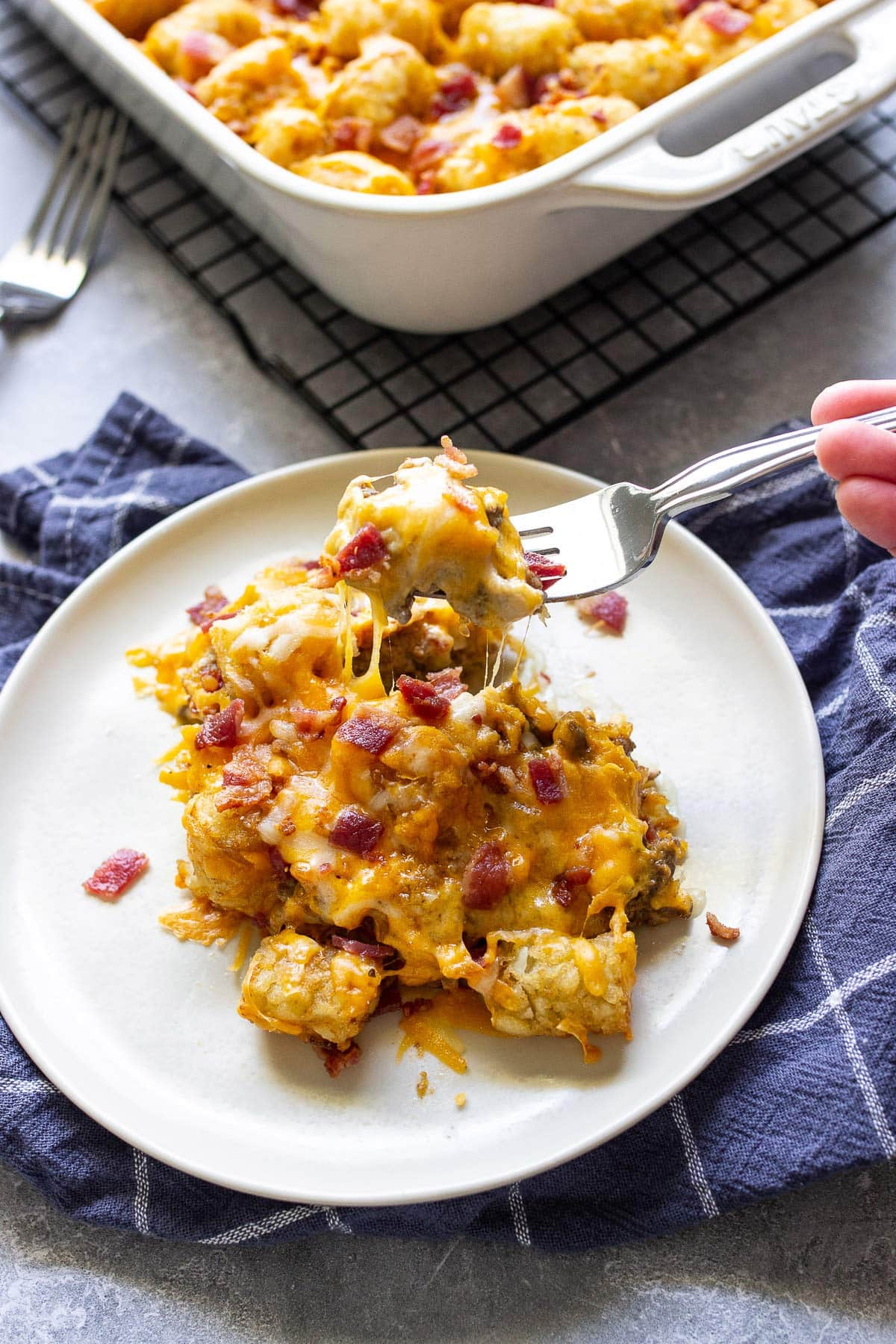 Multiple cheese strings from bacon cheeseburger tater tot casserole on a fork.