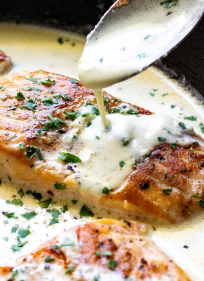 A close up shot of sauce drizzled over creamy garlic butter salmon.