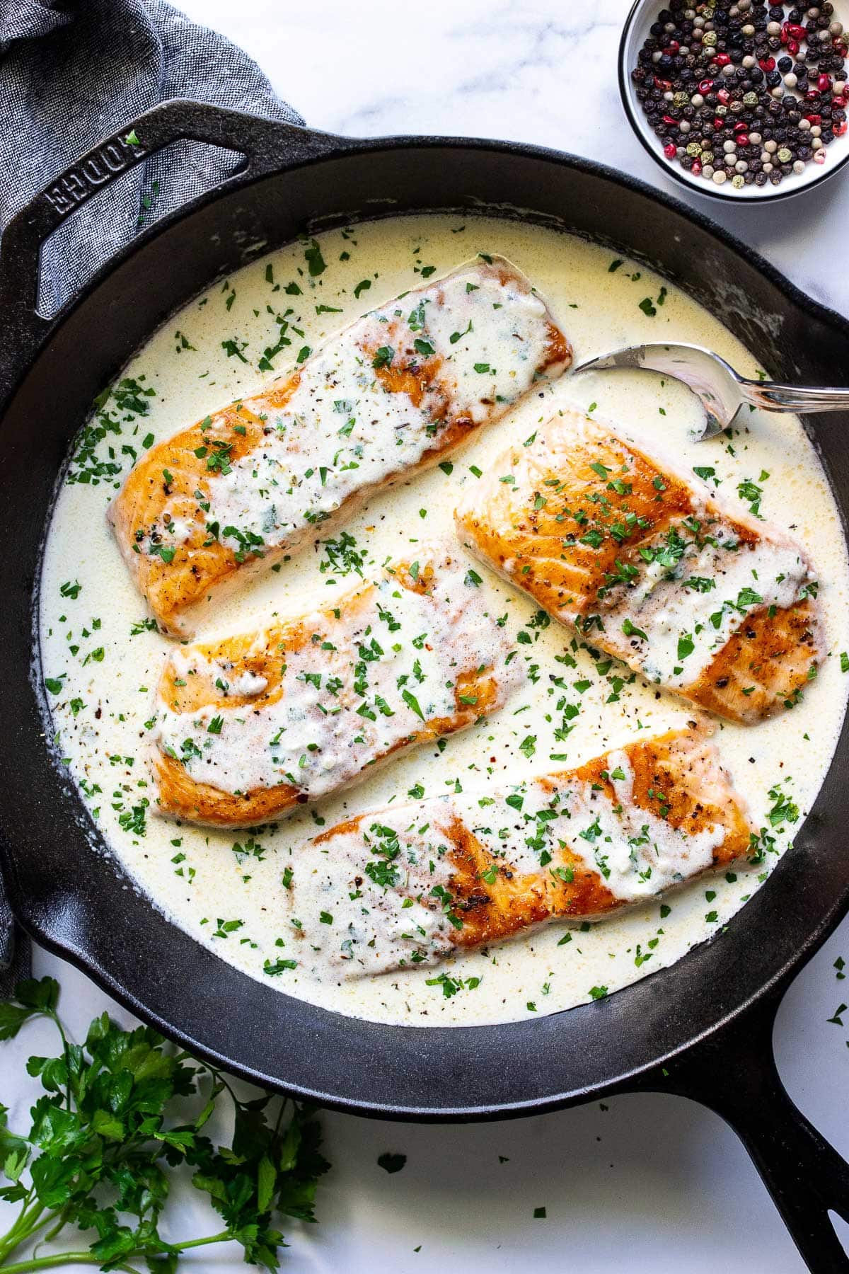 Creamy garlic butter salmon in a cast iron pan smothered in sauce and topped with fresh parsley.