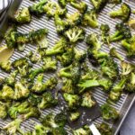 Garlic Parmesan roasted broccoli on a sheet pan topped with Parmesan cheese.