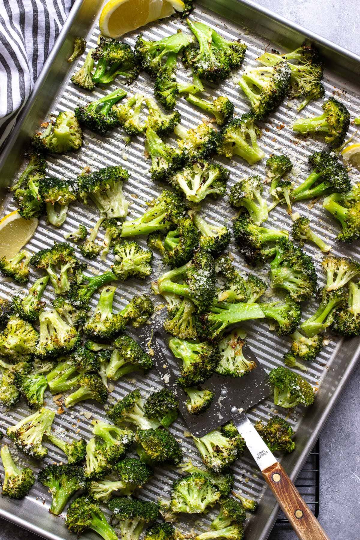 Garlic Parmesan roasted broccoli on a sheet pan topped with Parmesan cheese.