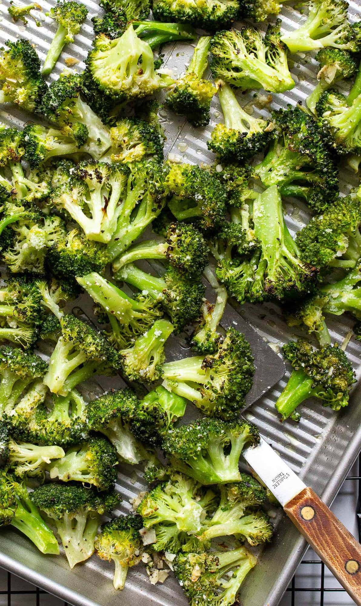 Garlic Parmesan roasted broccoli on a sheet pan topped with Parmesan cheese.